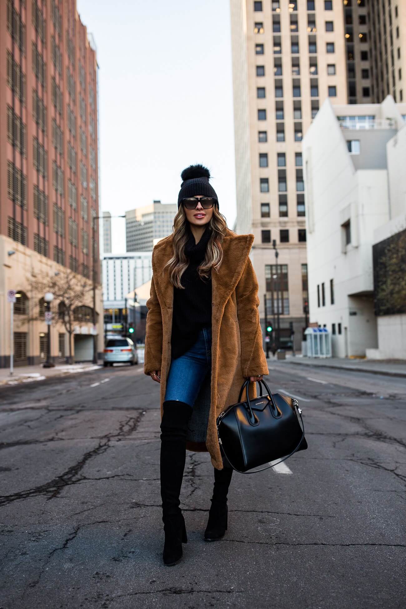 fashion blogger mia mia mine wearing a camel faux fur coat and a black pom pom beanie
