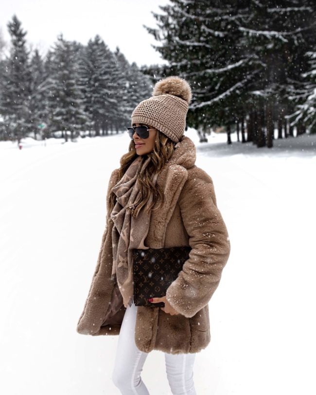 fashion blogger mia mia mine wearing a faux fur coat from revolve with a louis vuitton pouch 26