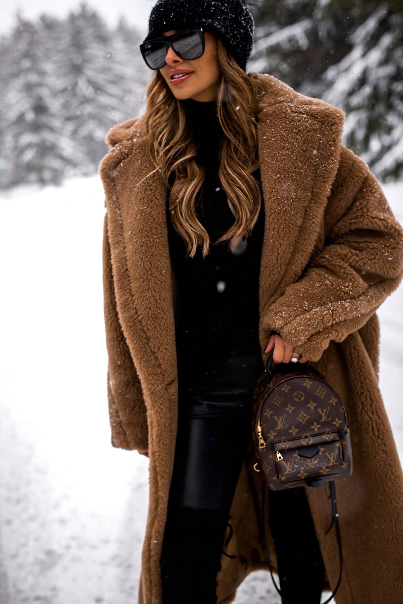fashion blogger mia mia mine wearing a camel coat and a louis vuitton palm springs mini backpack