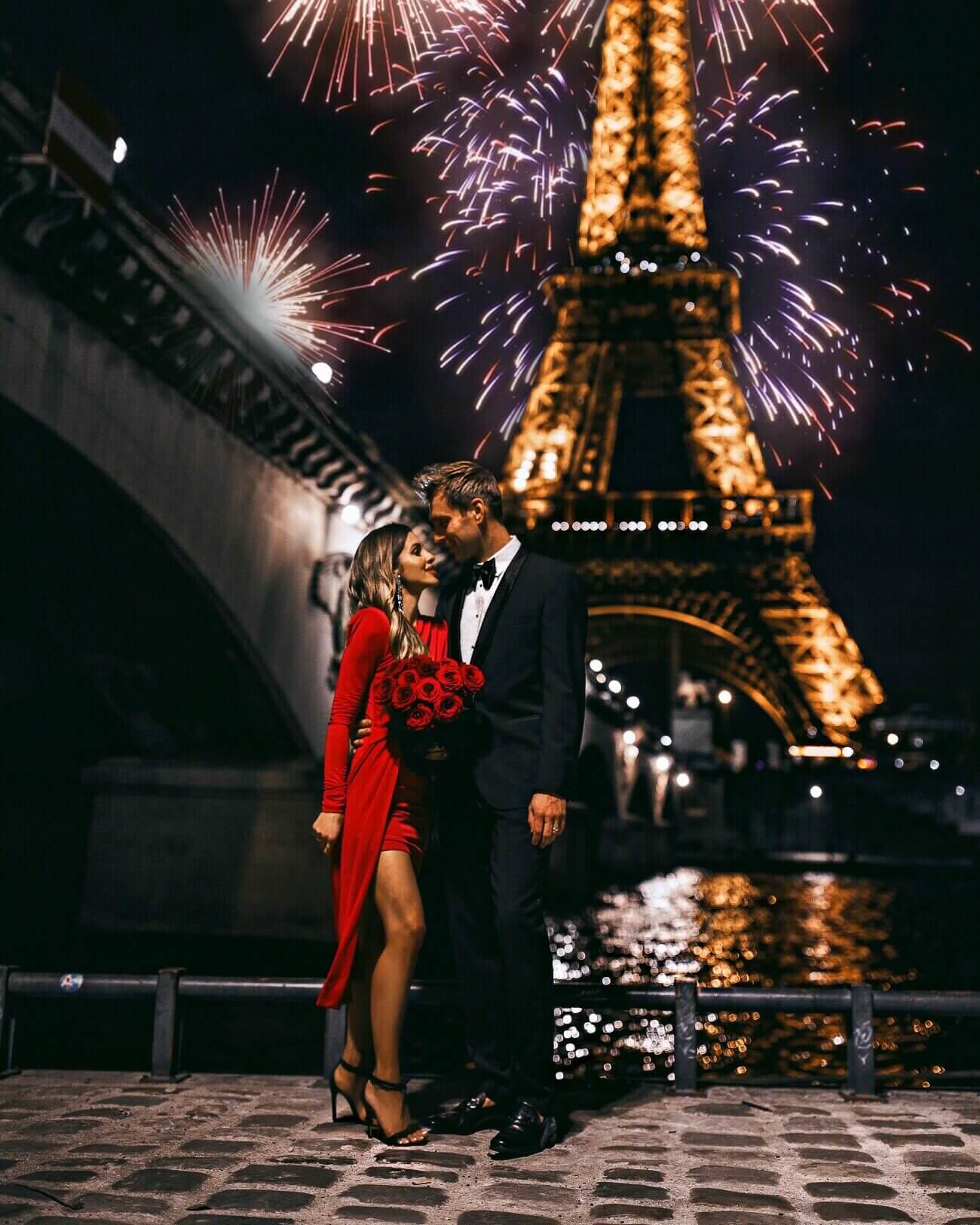 fashion blogger mia mia mine wearing a red dress with husband in front of the eiffel tower paris