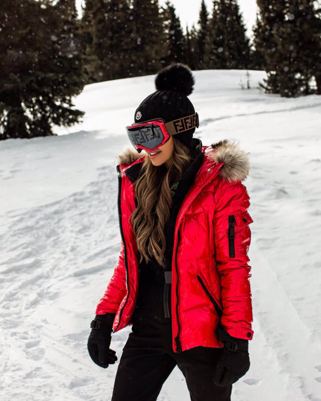 fashion blogger mia mia mine wearing a red puffer coat and fendi ski goggles