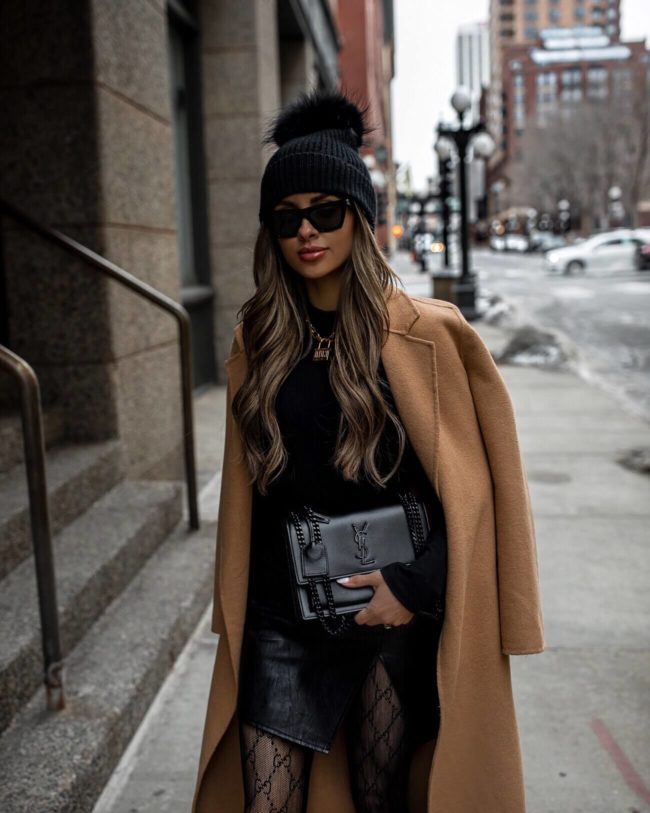 fashion blogger mia mia mine wearing a camel coat and black pom pom beanie