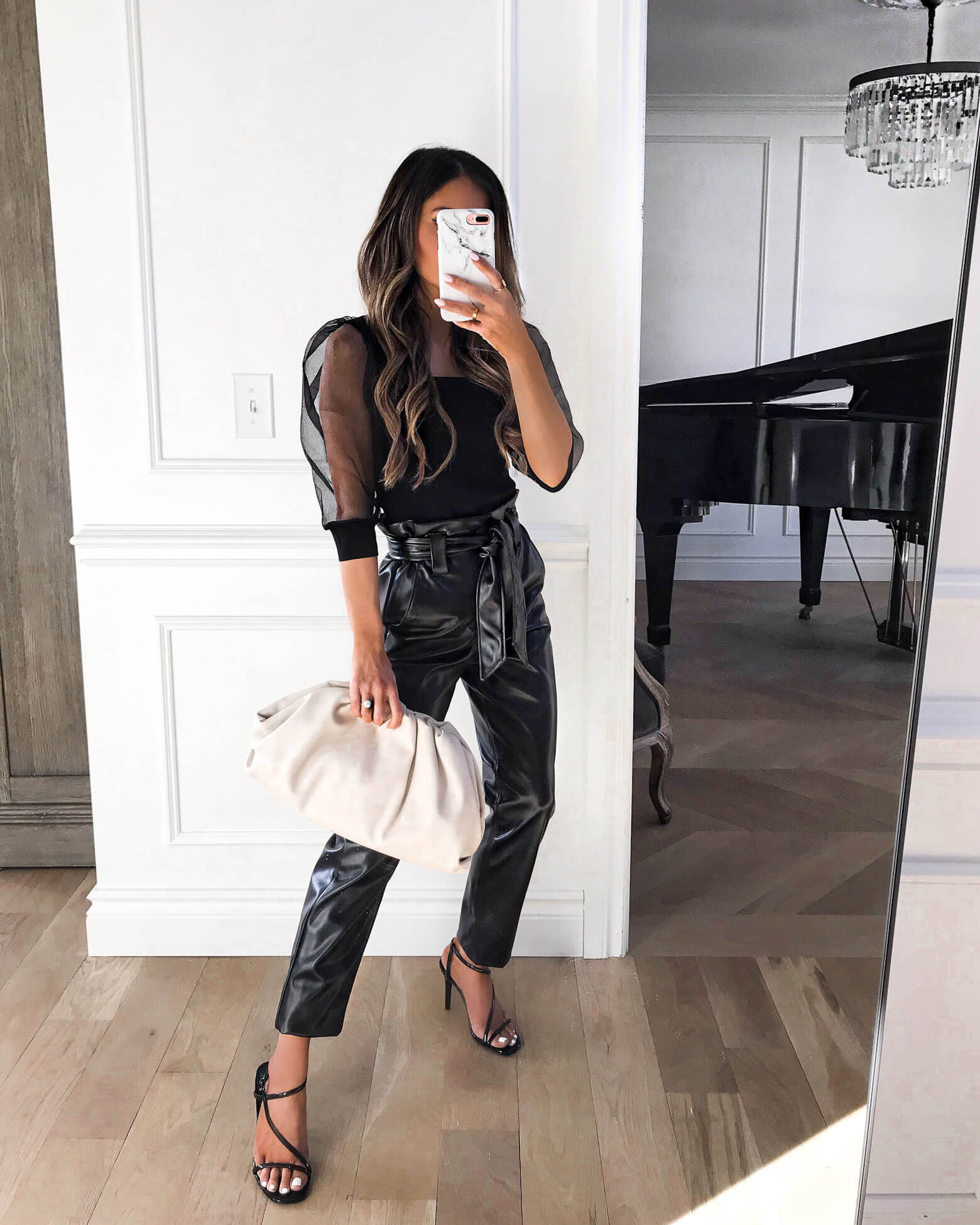 fashion blogger mia mia mine wearing black faux leather pants and a sheer sleeve top with a bottega veneta the pouch bag