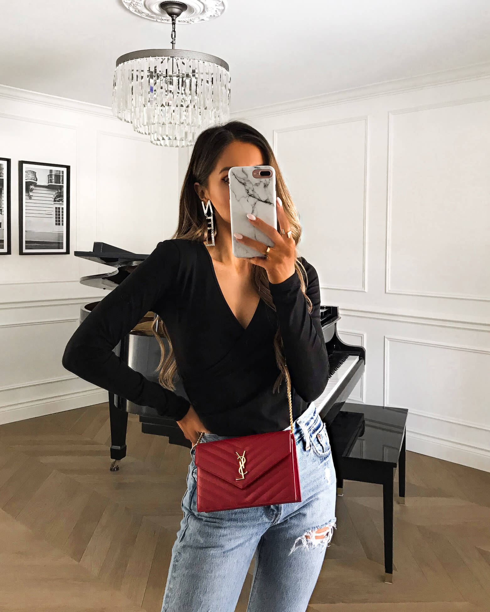 fashion blogger mia mia mine wearing a black v-neck bodysuit with a red saint laurent bag