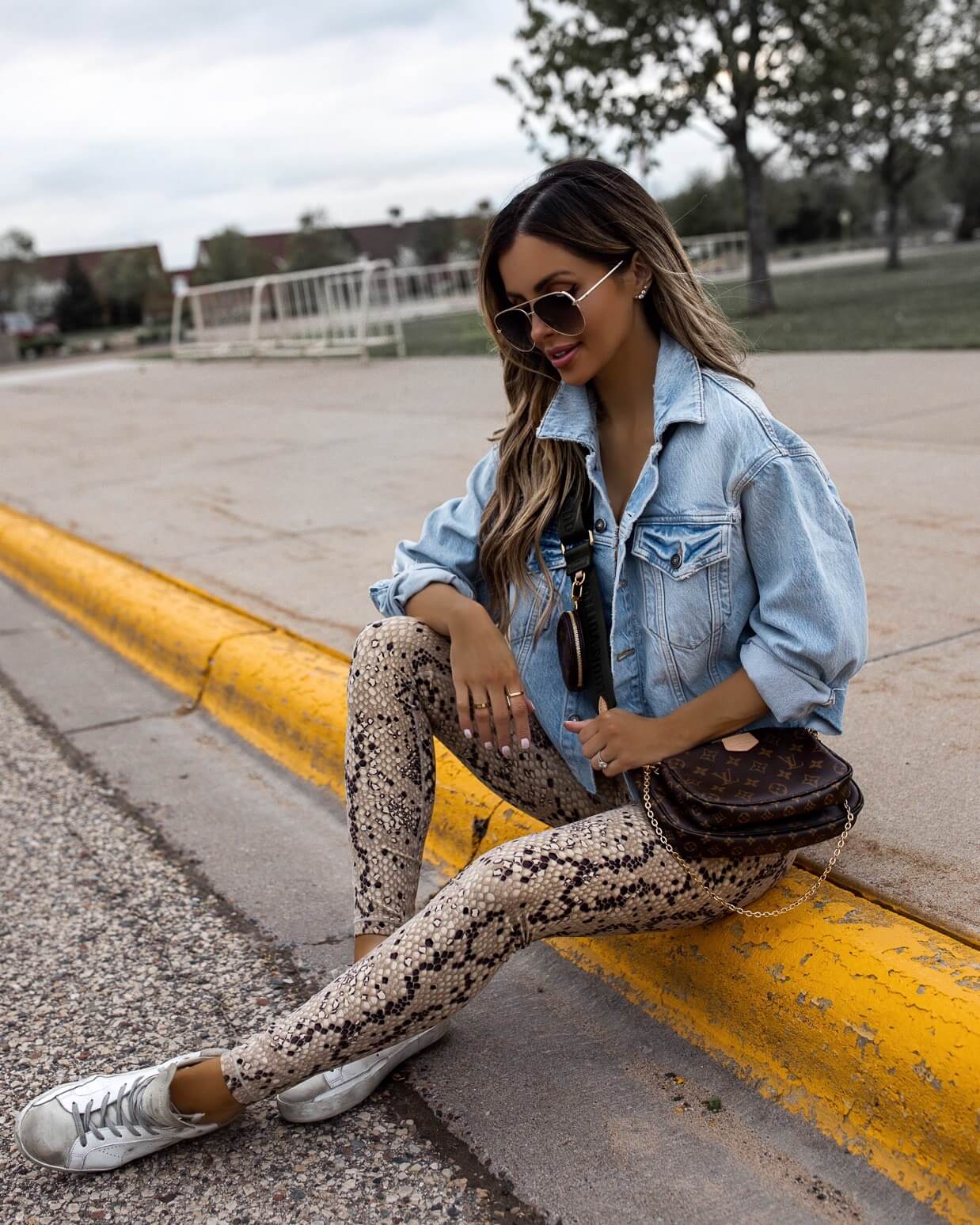 fashion blogger mia mia mine wearing snakeskin leggings from revolve and a denim jacket with louis vuitton multi pochette accessories