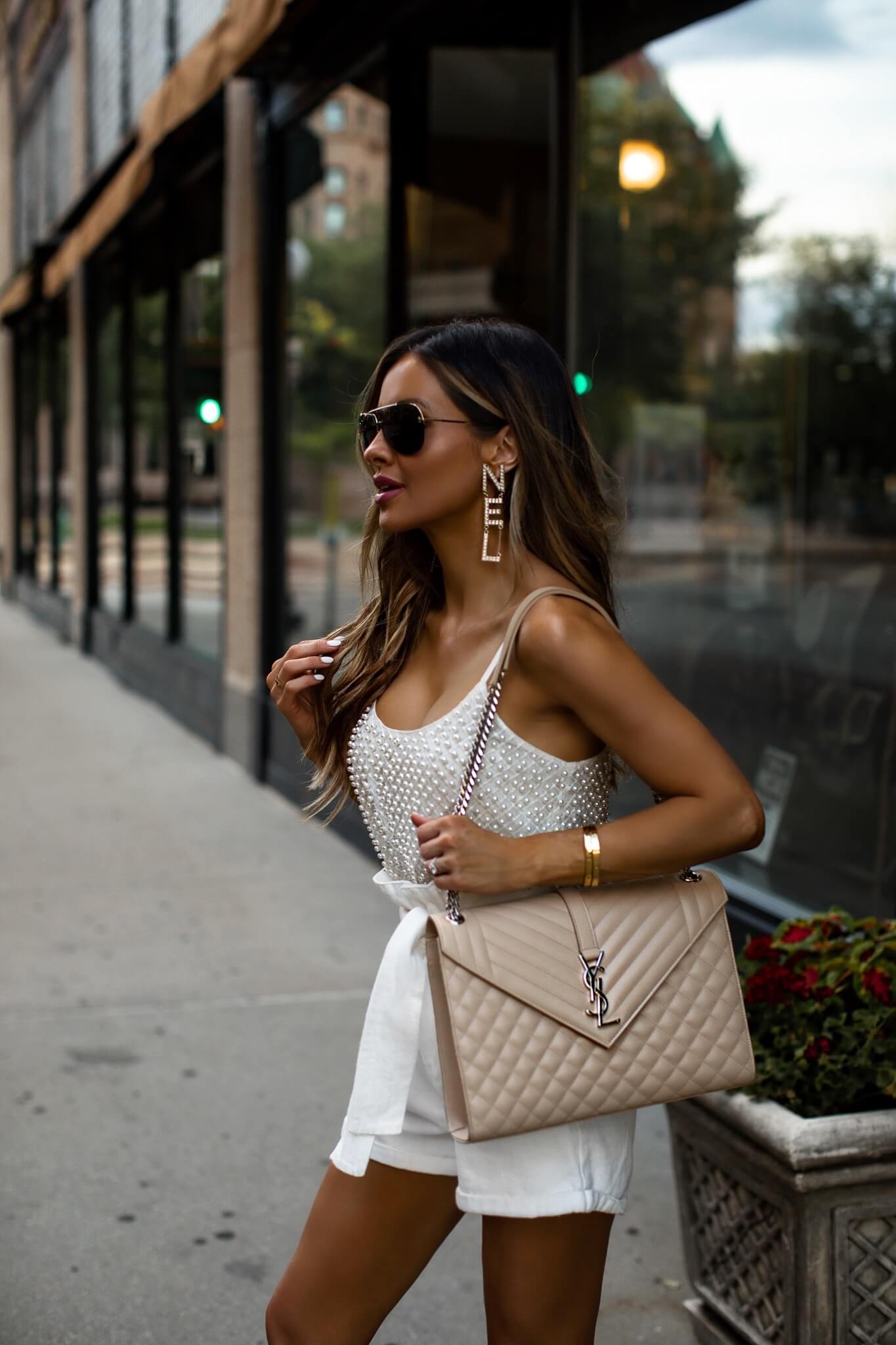 fashion blogger mia mia mine wearing a beaded tank top and white shorts with chanel earrings for summer