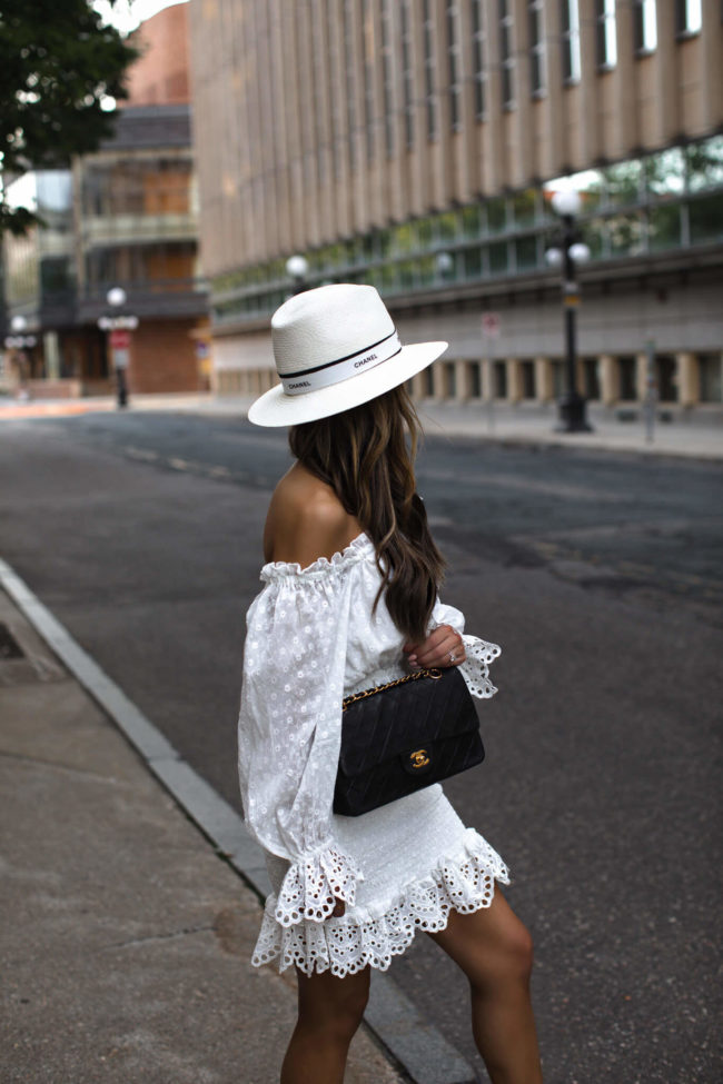 fashion blogger mia mia mine wearing a white eyelet dress and a chanel hat
