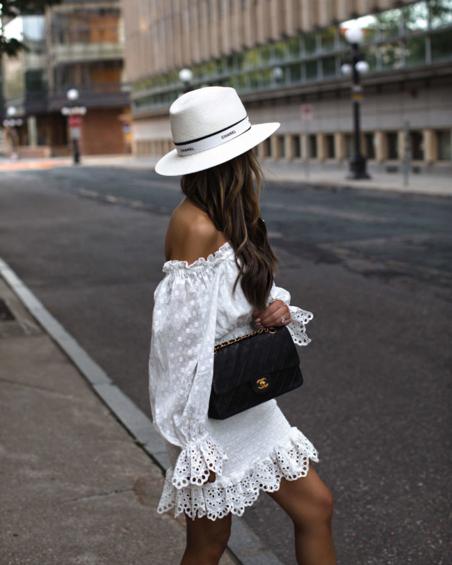 fashion blogger mia mia mine wearing a white eyelet dress and a chanel hat