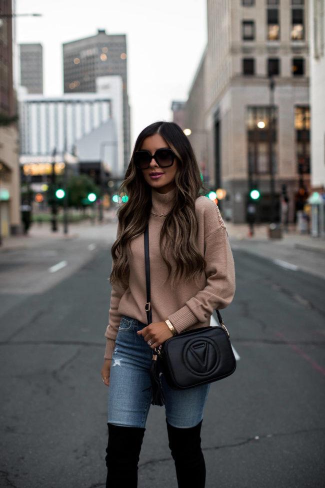 fashion blogger mia mia mine wearing a camel sweater and a black crossbody valentino bag from saks off 5th
