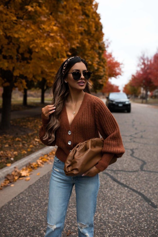 fashion blogger wearing a burnt orange cardigan and a bottega veneta pouch