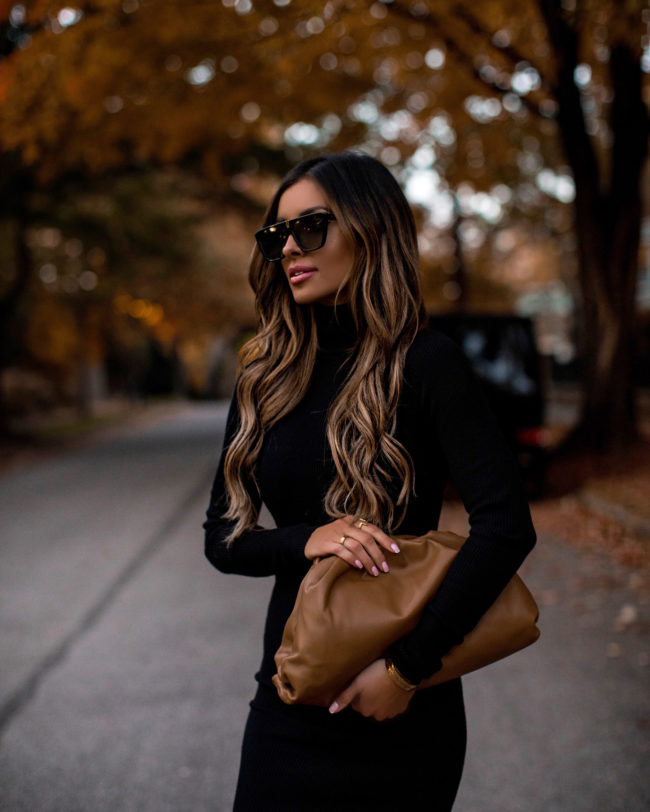 fashion blogger mia mia mine wearing a black sweater dress and a bottega veneta bag for fall