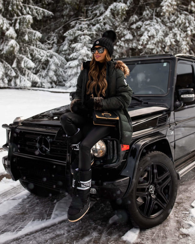 fashion blogger mia mia mine wearing a green winter coat and moon boots for winter