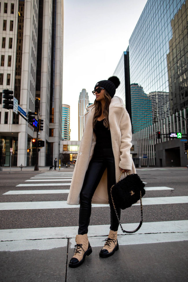 fashion blogger mia mia mine wearing a faux shearling jacket from express with chanel combat boots and chanel 19 bag
