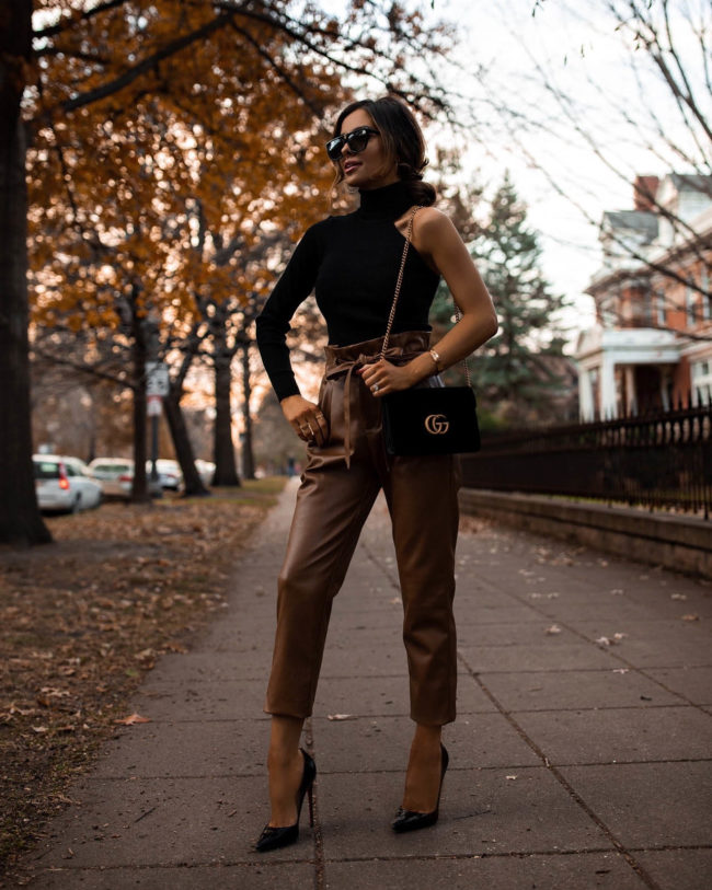 fashion blogger mia mia mine wearing a one shoulder sweater and brown leather pants from bloomingdales