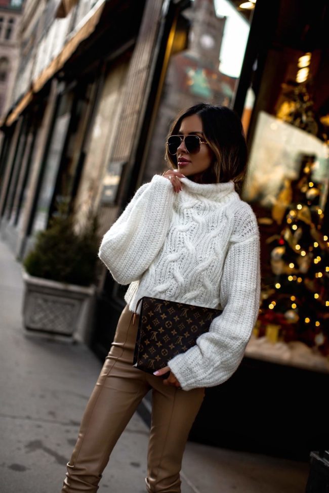 fashion blogger mia mia mine wearing a white chunky knit sweater and faux leather pants from revolve