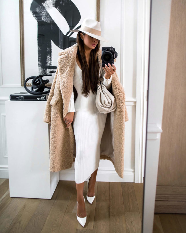 fashion blogger mia mia mine wearing a white sweater dress and a teddy bear coat from revolve for winter