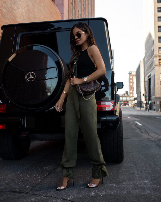 fashion blogger mia mia mine wearing a black halter top and olive green linen pants from revolve