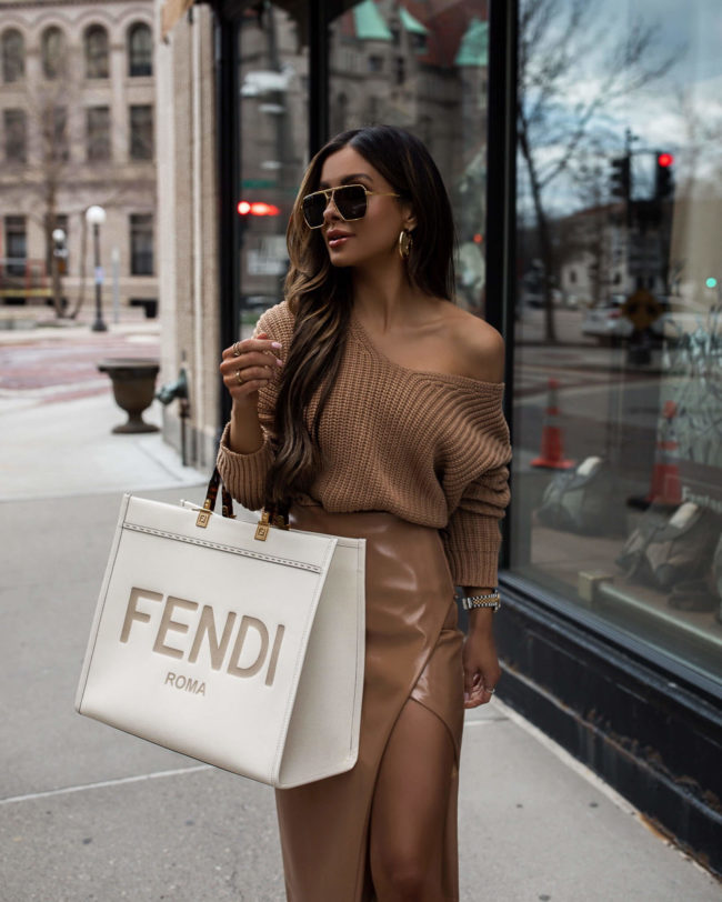 mia mia mine wearing a camel off the shoulder sweater with a camel patent leather skirt from revolve