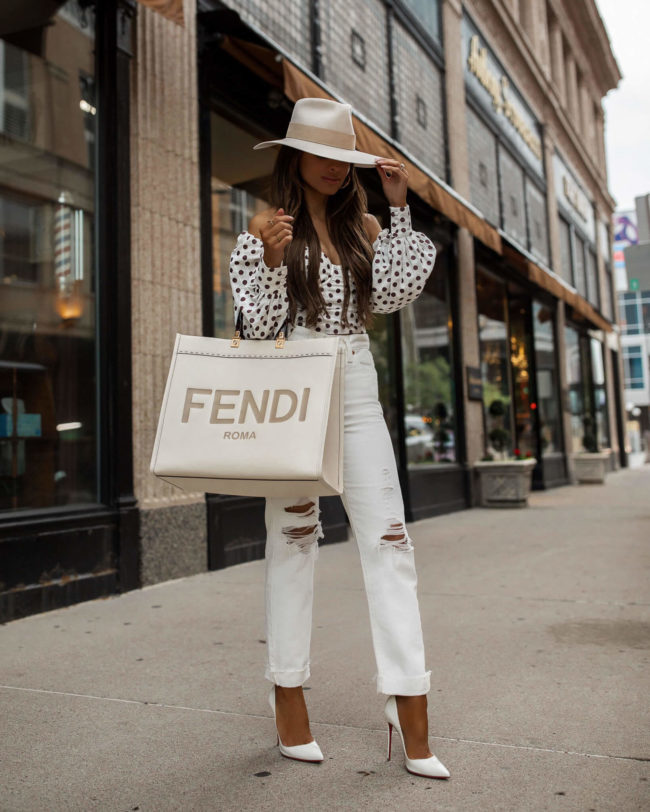 fashion blogger mia mia mine wearing a white outfit from revolve with a fendi sunshine tote