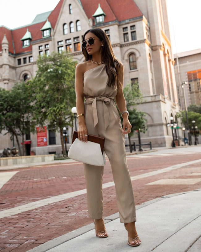 fashion blogger mia mia mine wearing a one shoulder tan jumpsuit from express