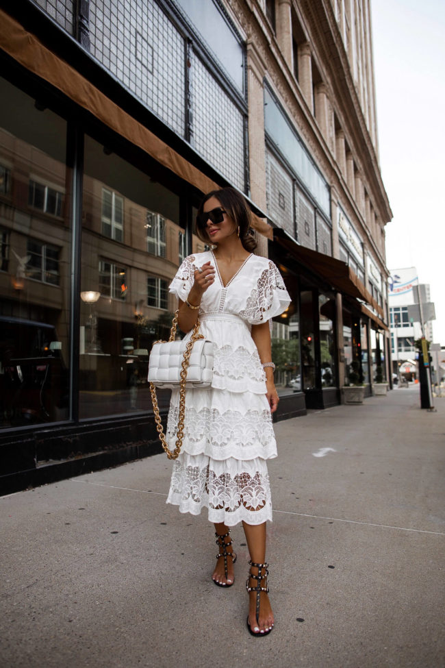 fashion blogger mia mia mine wearing a white lace dress and valentino rockstud sandals from neiman marcus