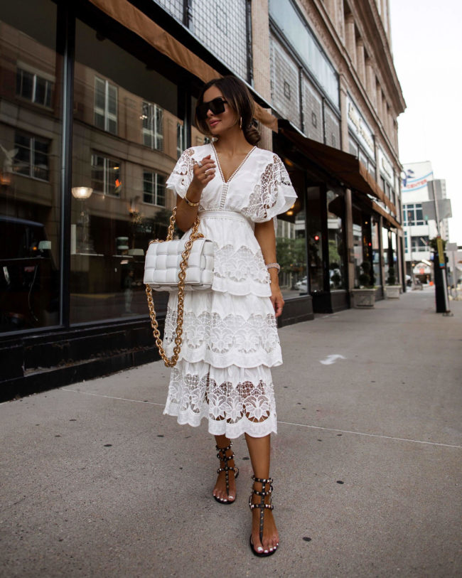 fashion blogger mia mia mine wearing a white lace dress and valentino rockstud sandals from neiman marcus