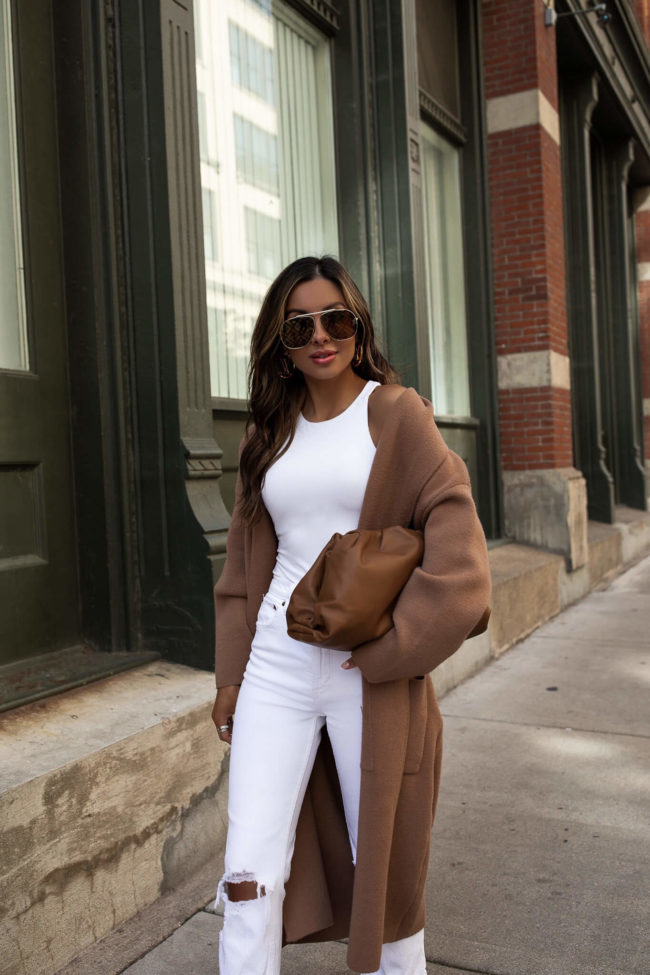 fashion blogger wearing a white outfit with a camel coat