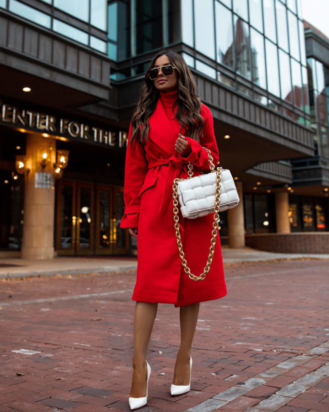 brunette fashion blogger wearing a red wrap coat and white bottega veneta bag