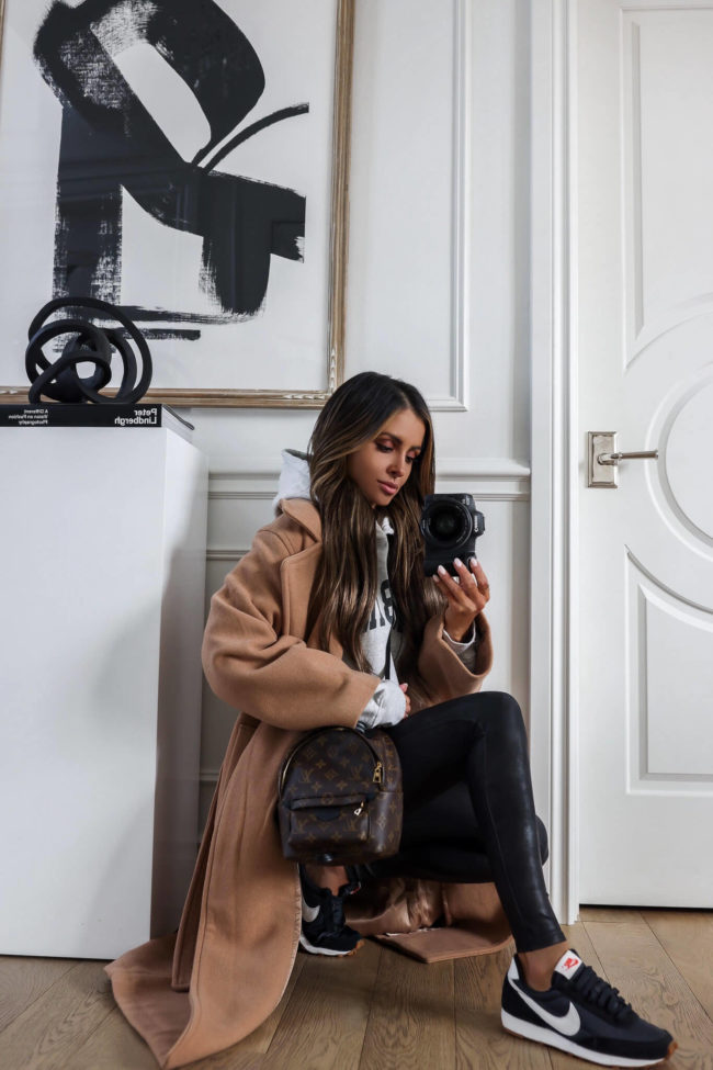 fashion blogger wearing an anine bing sweatshirt and a camel coat and nike daybreak sneakers