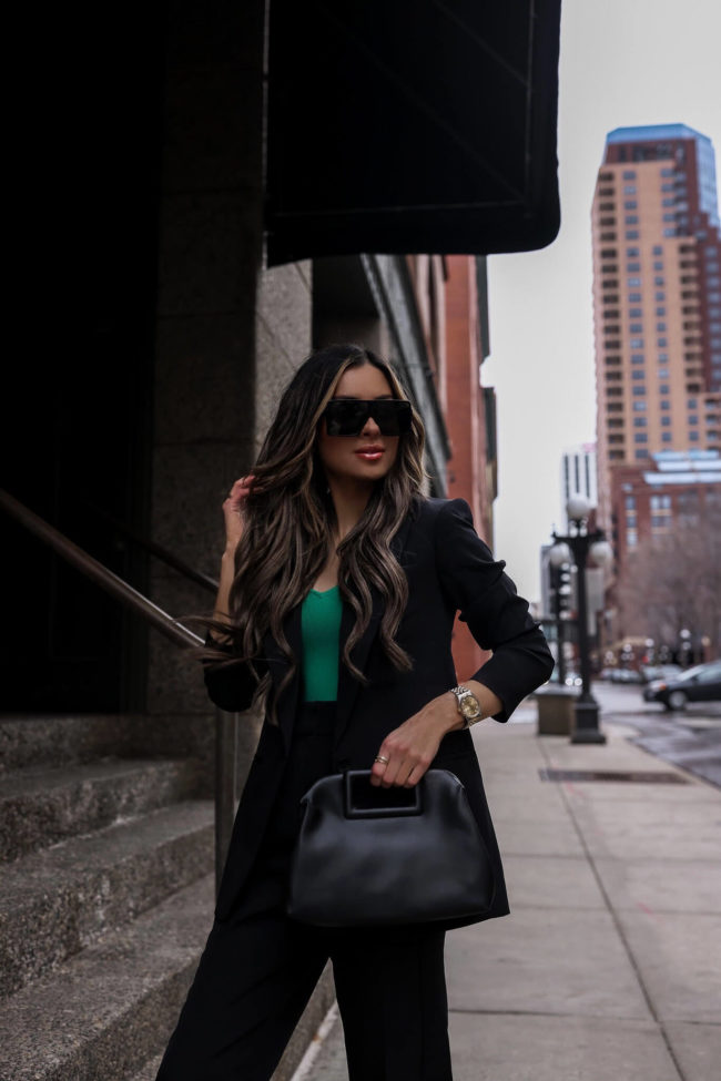 fashion blogger mia mia mine wearing a black suit from express with a green cami