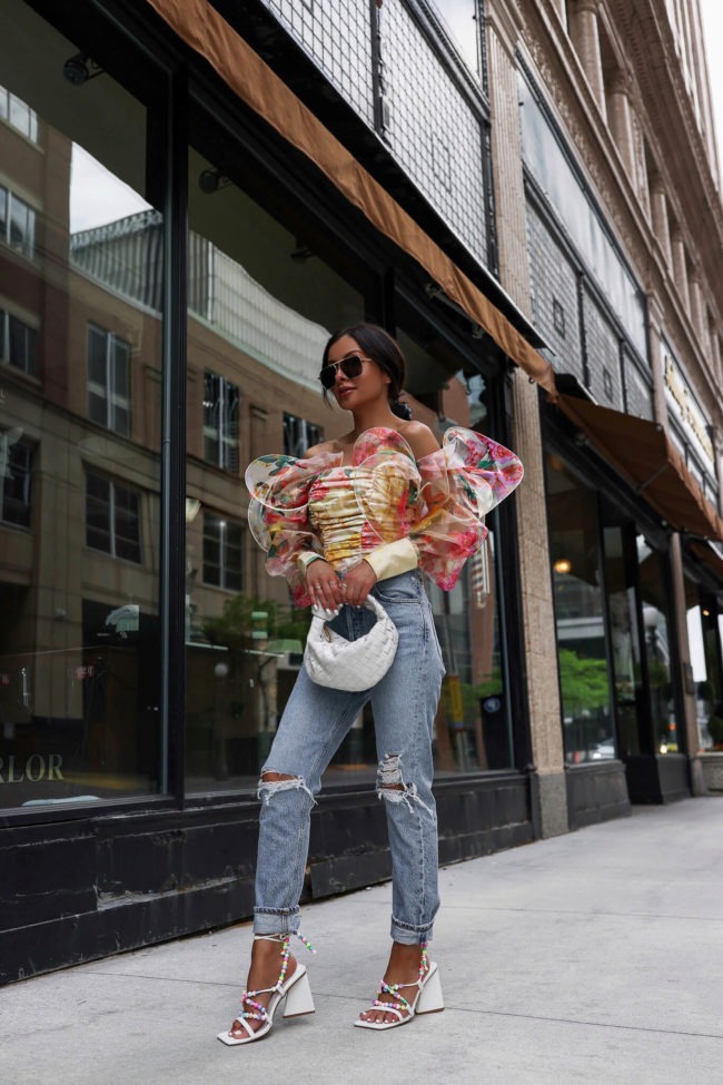 fashion blogger wearing a floral print top and cutout denim on the street