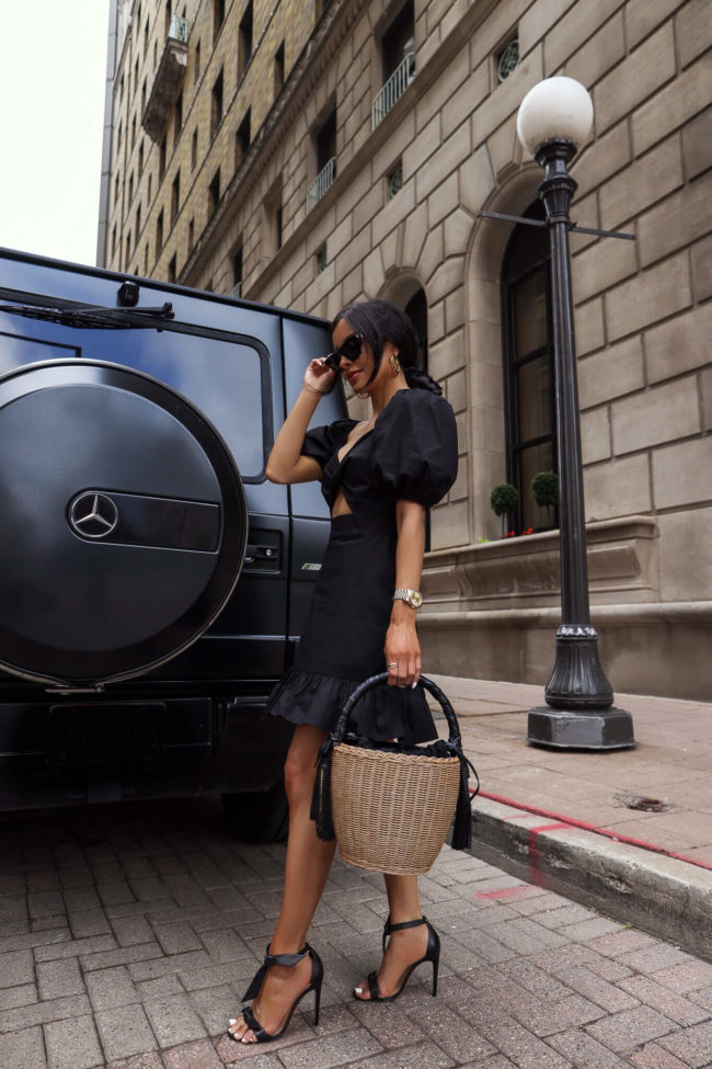 fashion blogger mia mia mine wearing a black summer dress with a saint laurent straw bag from saks
