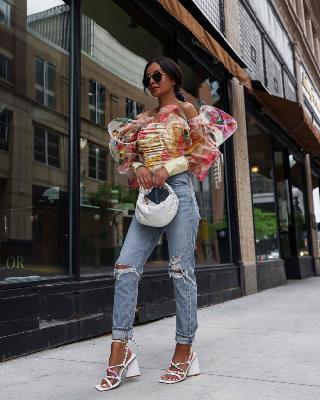 fashion blogger wearing a floral print top and cutout denim on the street