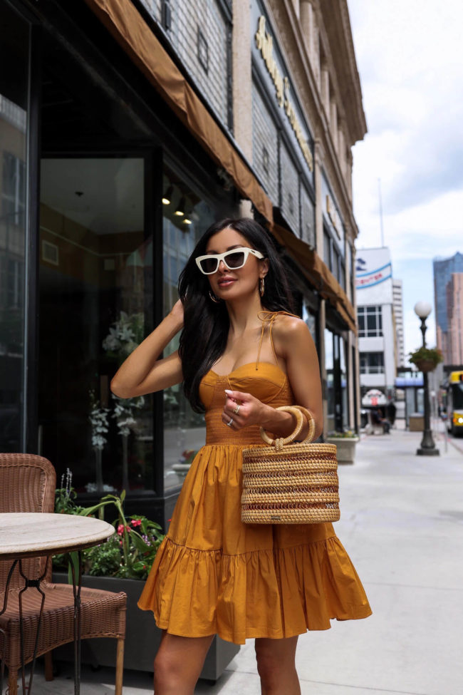 brunette fashion blogger wearing a bustier dress and cult gaia bag from saks
