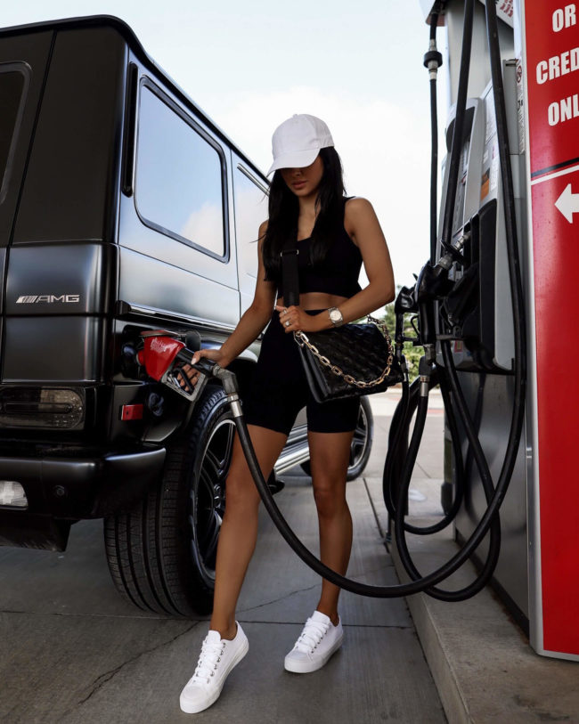 brunette woman pumping gas in a summer outfit