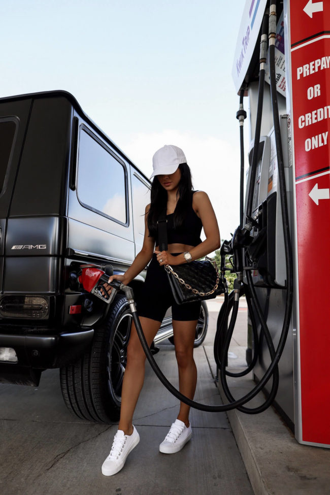 brunette woman pumping gas in a summer outfit
