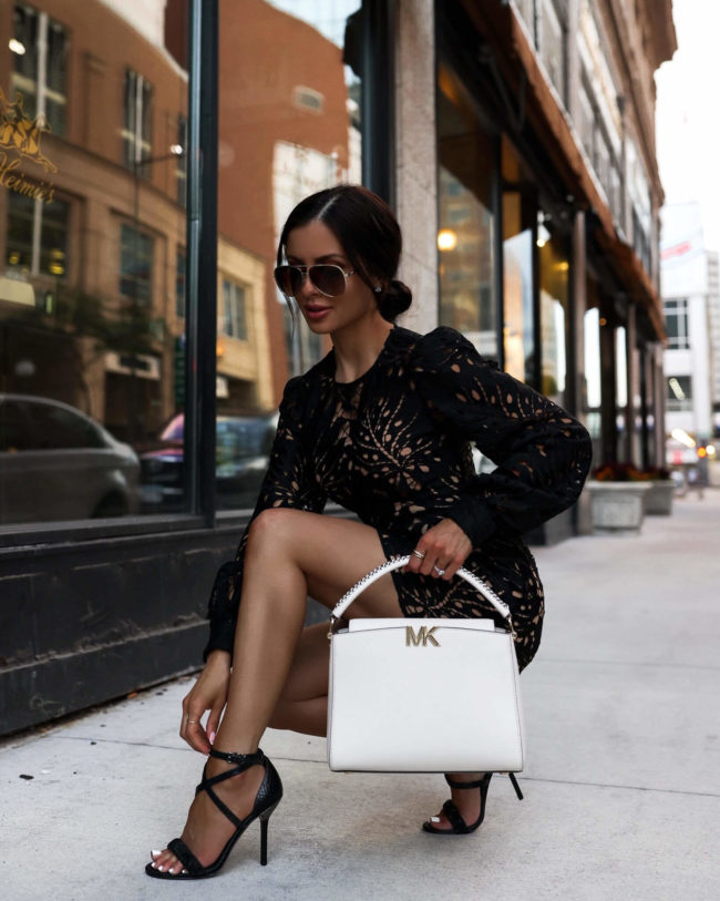 fashion blogger mia mia mine wearing a black lace dress and black heels by michael kors