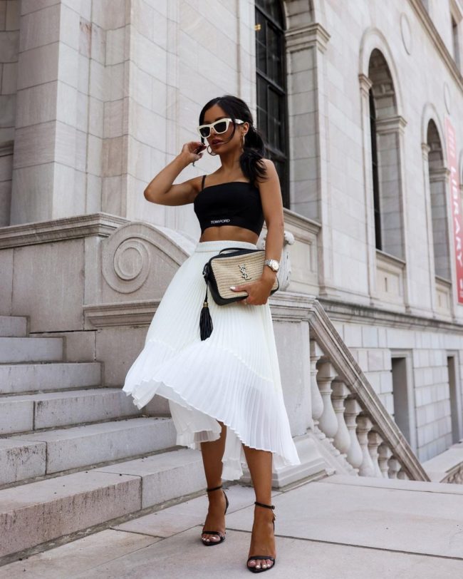 fashion blogger mia mia mine wearing a tom ford sports bra with a white pleated skirt