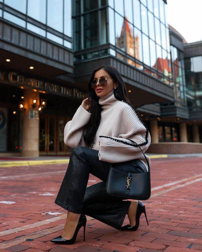 fashion blogger mia mia mine wearing coated denim pants and a chunky knit sweater from neiman marcus