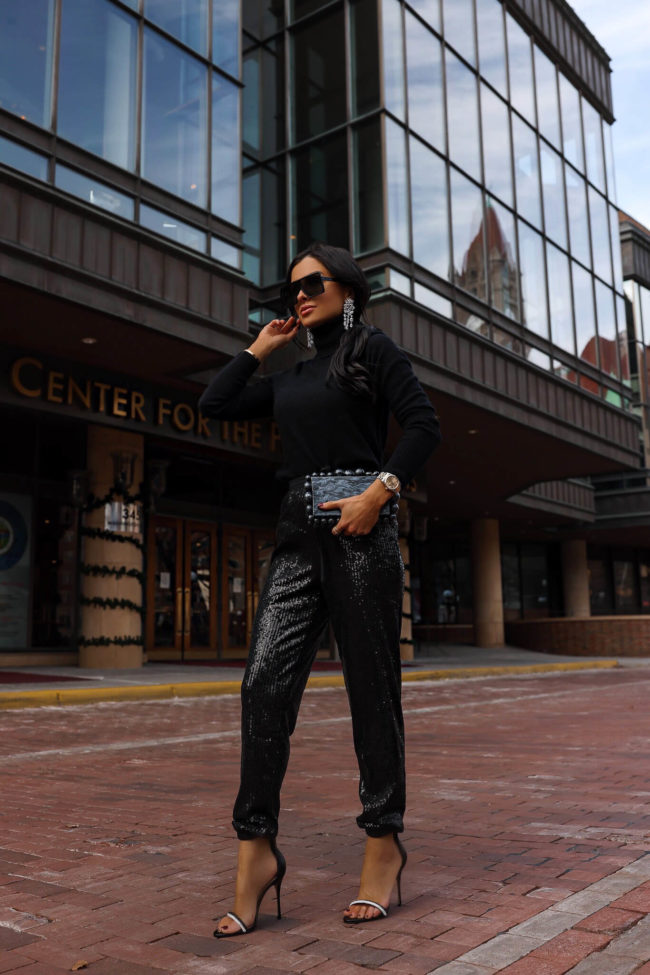 fashion blogger mia mia mine wearing sequin jogger pants and a black turtleneck sweater from bloomingdales