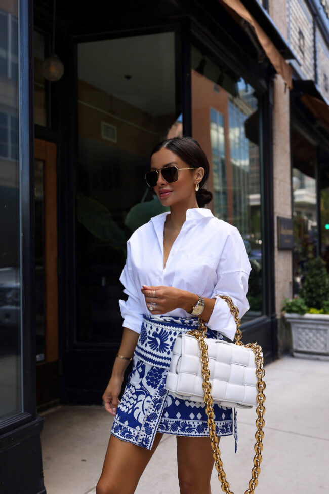 fashion blogger mia mia mine wearing a white button down shirt and a blue and white skirt from saks