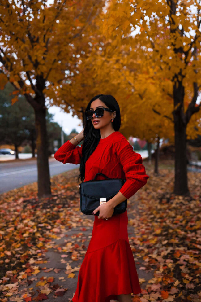fashion blogger mia mia mine wearing a red sweater and dress for fall