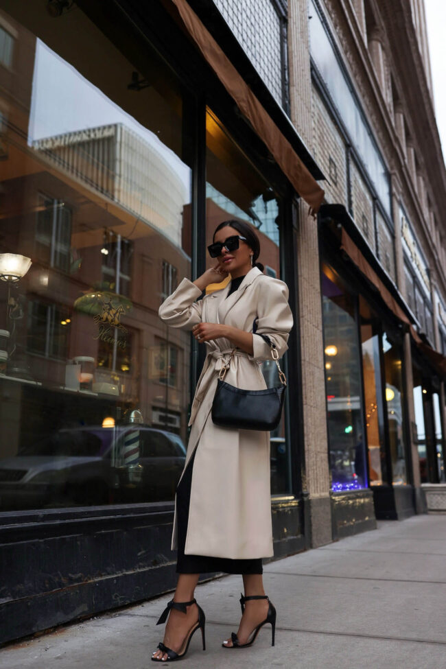 fashion blogger wearing a camel trench coat and a black bag for spring