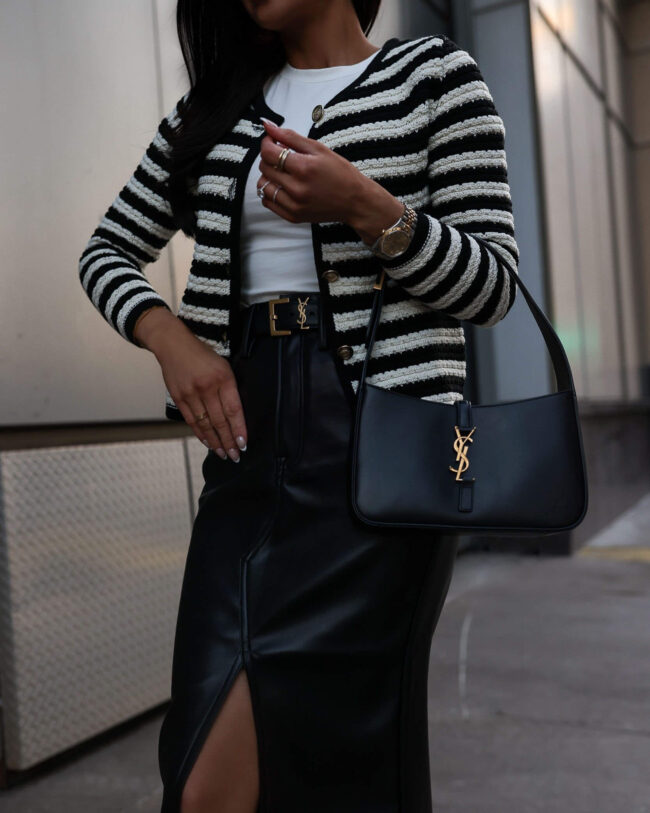 fashion blogger mia mia mine wearing a striped cardigan with a faux leather skirt and a saint laurent belt