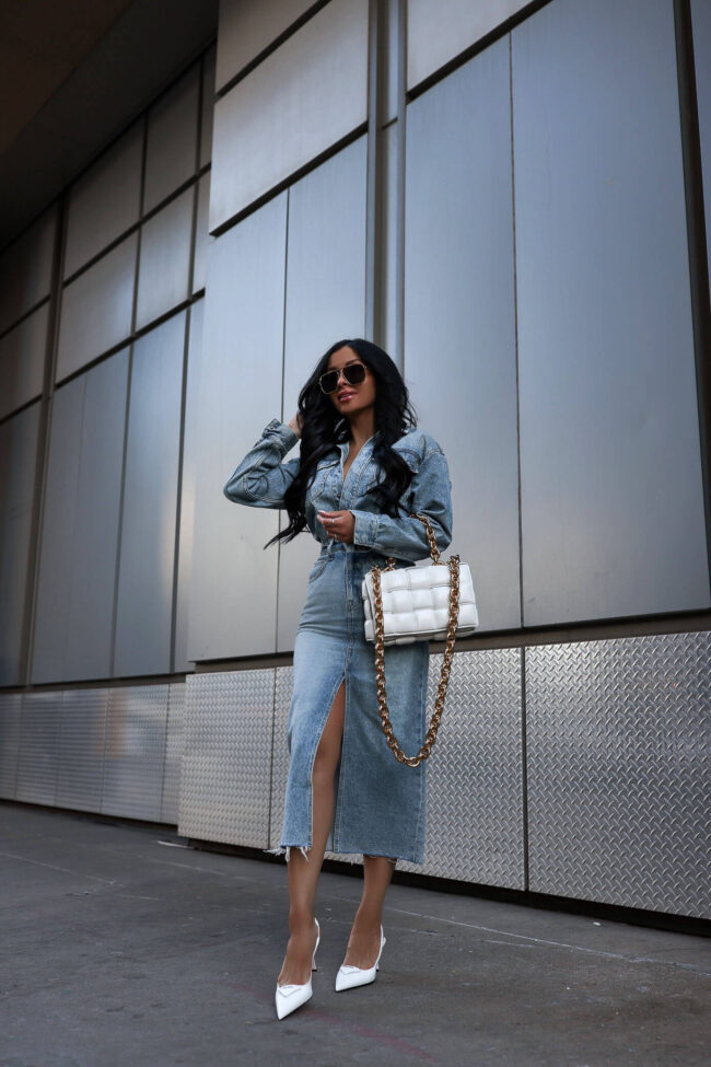 fashion blogger wearing a denim dress and white prada heels