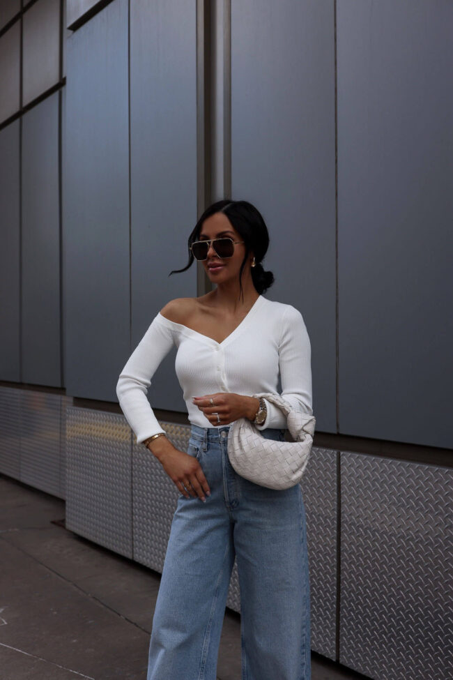 fashion blogger wearing a white off shoulder knit top by staud
